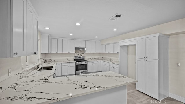 kitchen featuring decorative backsplash, white cabinetry, light stone countertops, stainless steel range, and sink