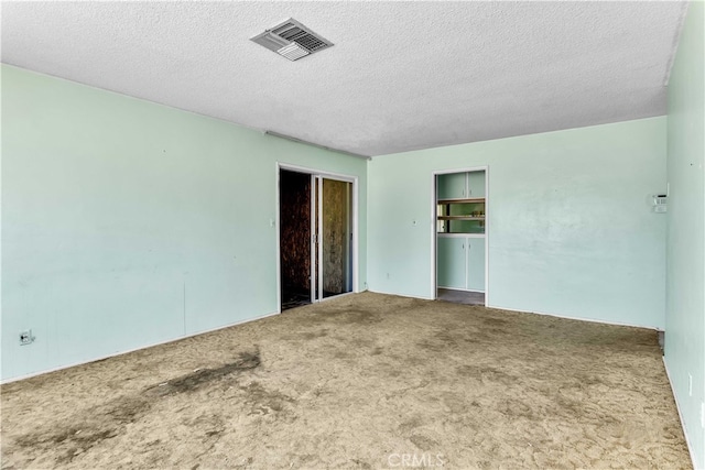 carpeted spare room with a textured ceiling