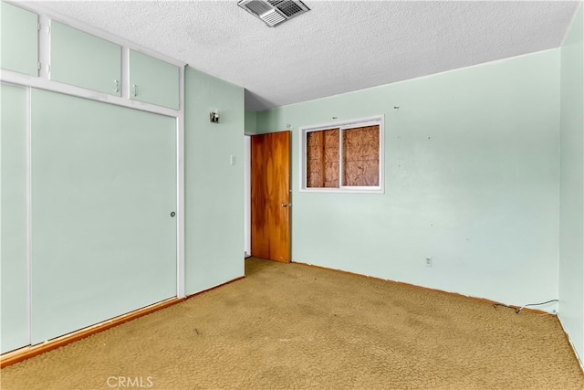 empty room with light carpet and a textured ceiling