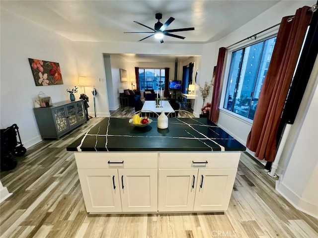 kitchen featuring ceiling fan, a kitchen island, light wood-type flooring, and white cabinetry