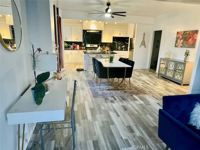 kitchen featuring white cabinets, light hardwood / wood-style floors, a breakfast bar area, and tasteful backsplash