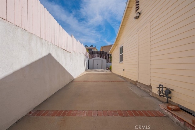 view of side of home featuring a patio area and a storage shed