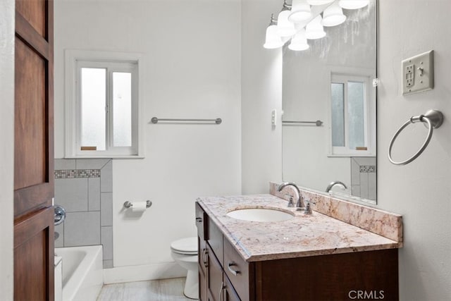 bathroom with toilet, vanity, and plenty of natural light