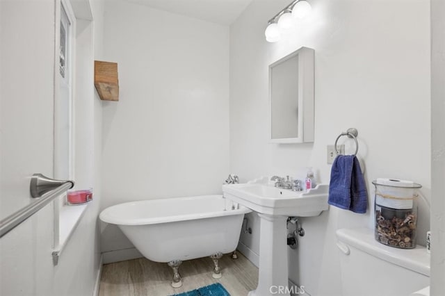 bathroom with toilet, a tub to relax in, and wood-type flooring