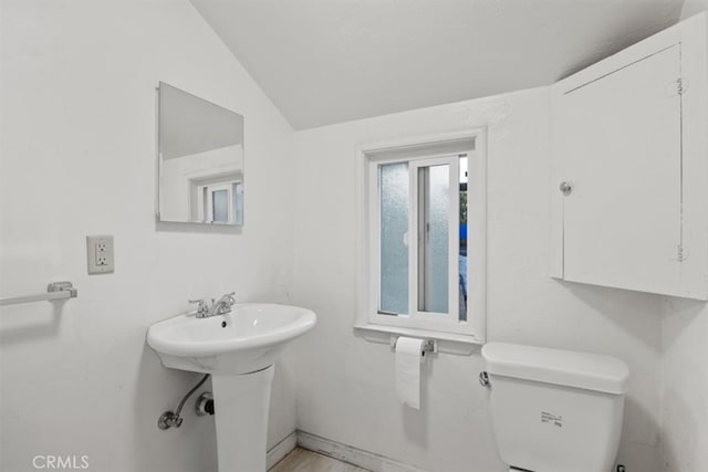 bathroom with toilet, sink, and vaulted ceiling