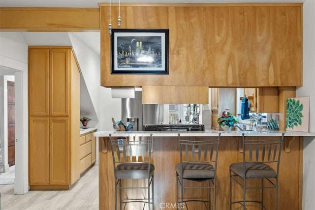 kitchen with light wood-type flooring, kitchen peninsula, and a breakfast bar area