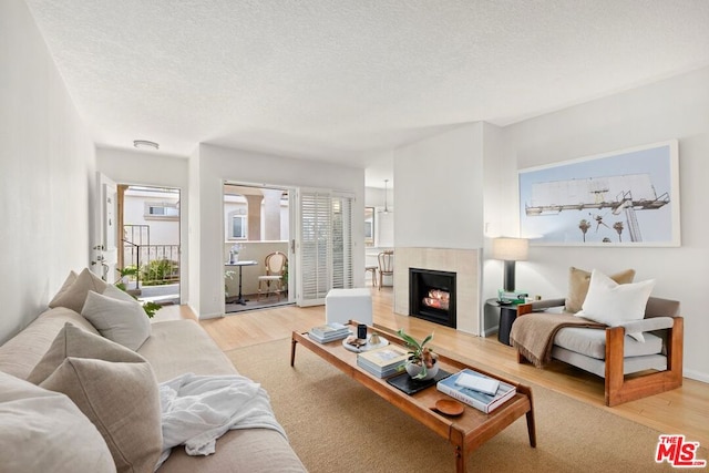 living room featuring a tile fireplace, light hardwood / wood-style flooring, and a textured ceiling