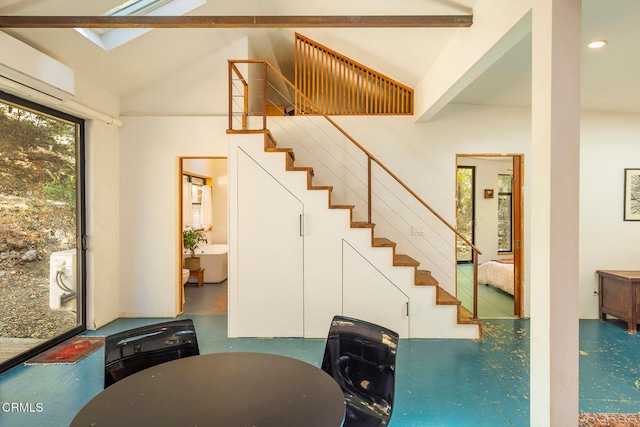 staircase featuring lofted ceiling with skylight and an AC wall unit