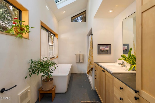 bathroom with vanity, concrete floors, a healthy amount of sunlight, and a bath