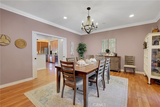 dining area featuring light hardwood / wood-style floors, crown molding, and a notable chandelier