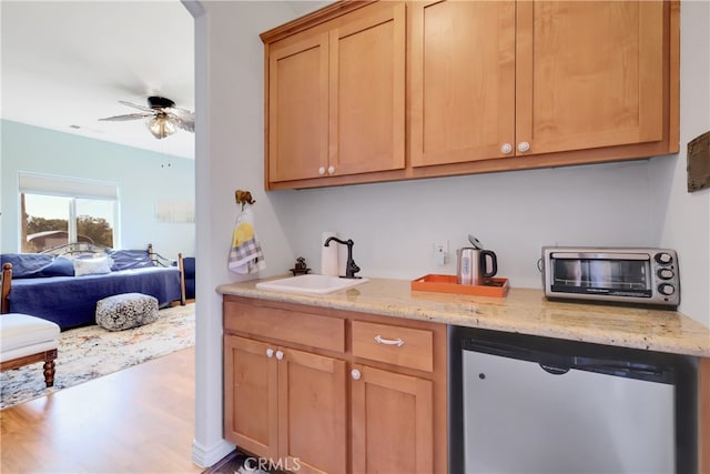 kitchen featuring ceiling fan, light stone countertops, hardwood / wood-style flooring, stainless steel refrigerator, and sink