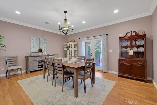 dining space with a notable chandelier, ornamental molding, french doors, and light wood-type flooring