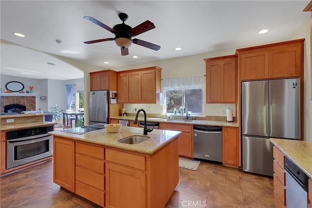 kitchen with a kitchen island with sink, stainless steel appliances, sink, and ceiling fan