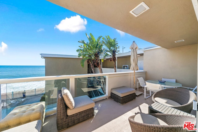 balcony featuring a water view and a beach view