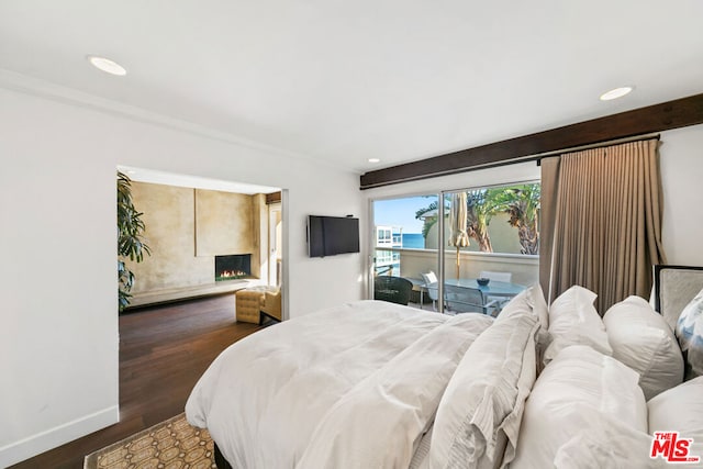 bedroom with access to outside, dark hardwood / wood-style floors, and a fireplace