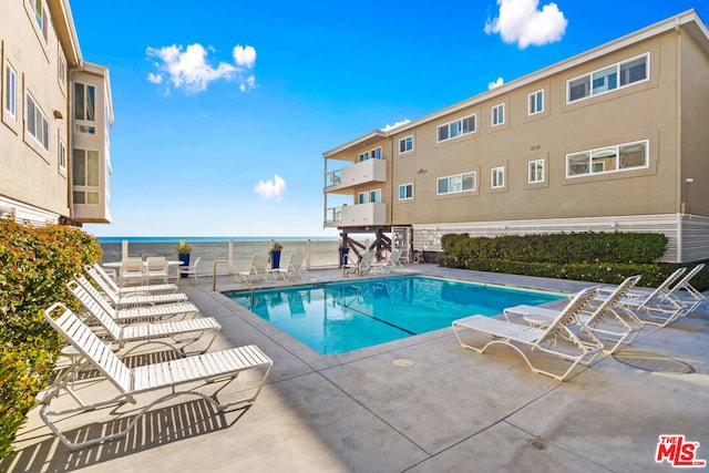 view of swimming pool with a water view and a patio