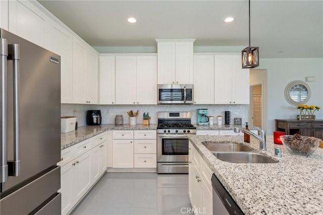 kitchen with pendant lighting, sink, white cabinets, and appliances with stainless steel finishes