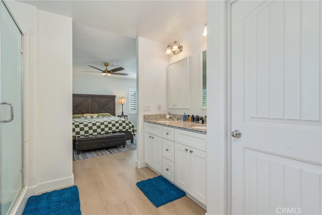 bathroom featuring ceiling fan, vanity, wood-type flooring, and walk in shower