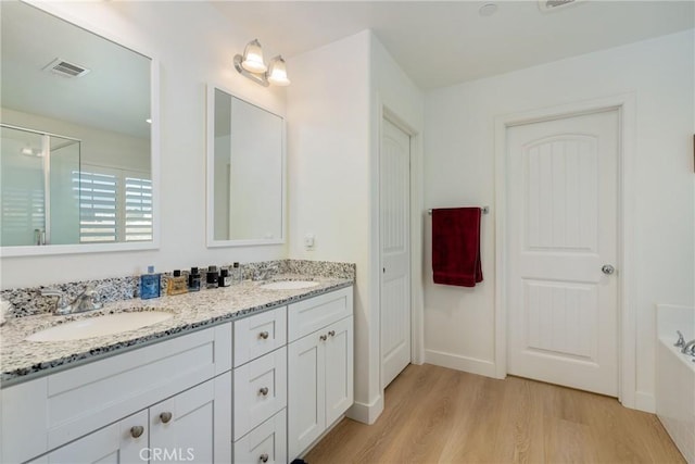 bathroom with a bath, wood-type flooring, and vanity