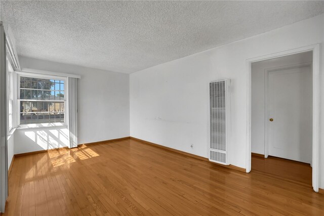 empty room featuring wood-type flooring and a textured ceiling