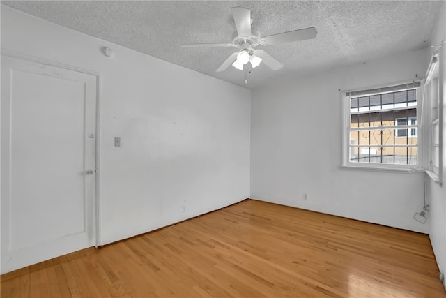 unfurnished room with ceiling fan, light wood-type flooring, and a textured ceiling