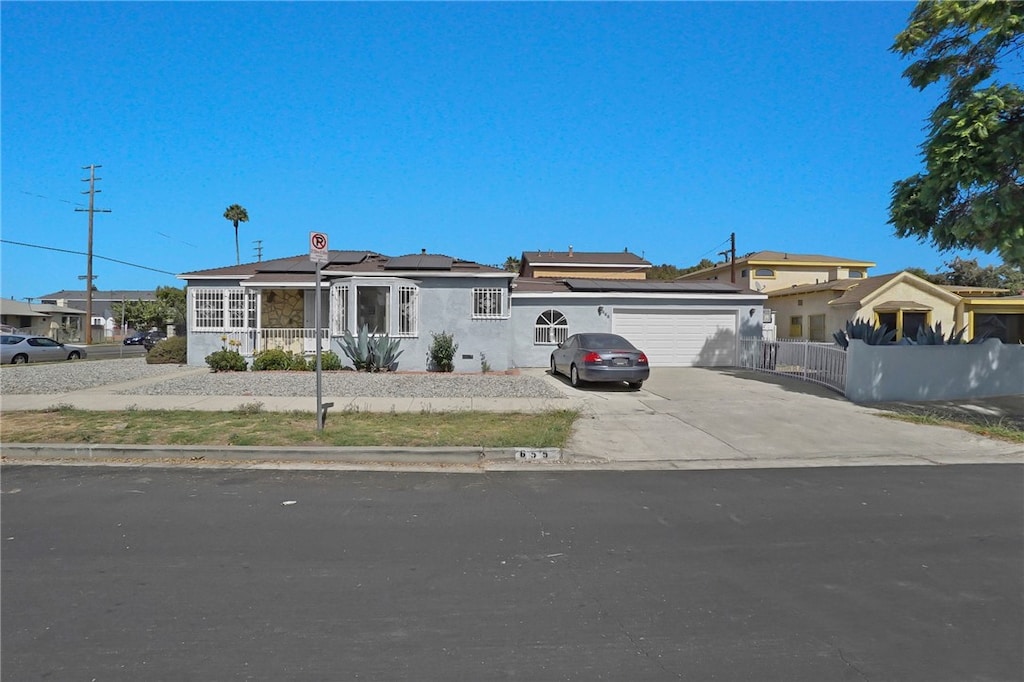 ranch-style house featuring a garage and solar panels