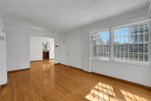 unfurnished room featuring wood-type flooring, a textured ceiling, and an inviting chandelier