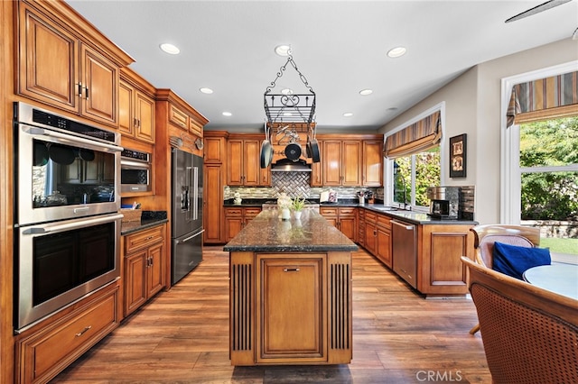 kitchen featuring backsplash, stainless steel appliances, light wood-type flooring, and a kitchen island