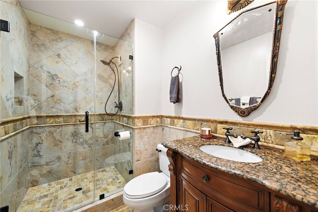 bathroom with tile walls, vanity, toilet, and walk in shower