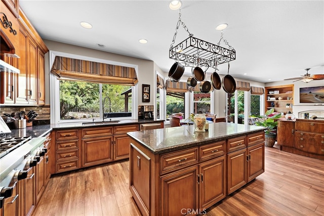 kitchen with a healthy amount of sunlight, light hardwood / wood-style flooring, dark stone counters, and a kitchen island