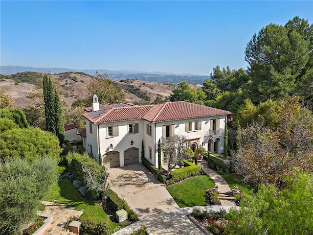 mediterranean / spanish-style home with a mountain view, a garage, and a front lawn