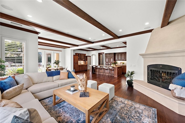 living room featuring a large fireplace, dark hardwood / wood-style floors, and beam ceiling