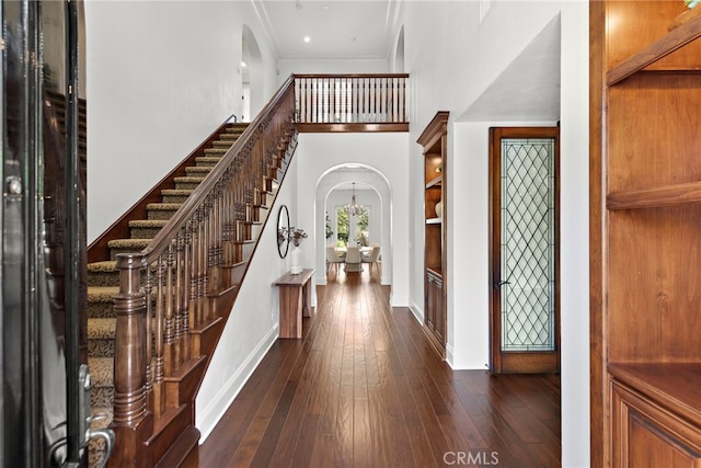 entryway with dark wood-type flooring and ornamental molding