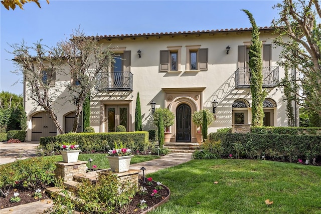 mediterranean / spanish-style home with a balcony and a front lawn