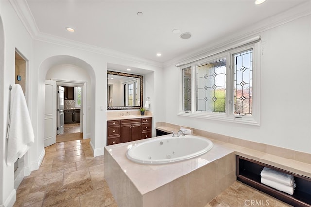 bathroom featuring tiled bath, vanity, and ornamental molding