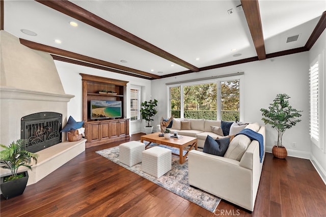 living room featuring beamed ceiling, a large fireplace, crown molding, and dark wood-type flooring