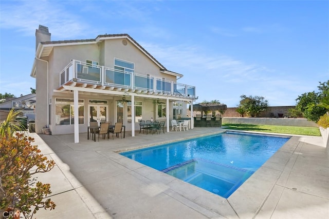 rear view of property with a patio, a balcony, and a swimming pool with hot tub