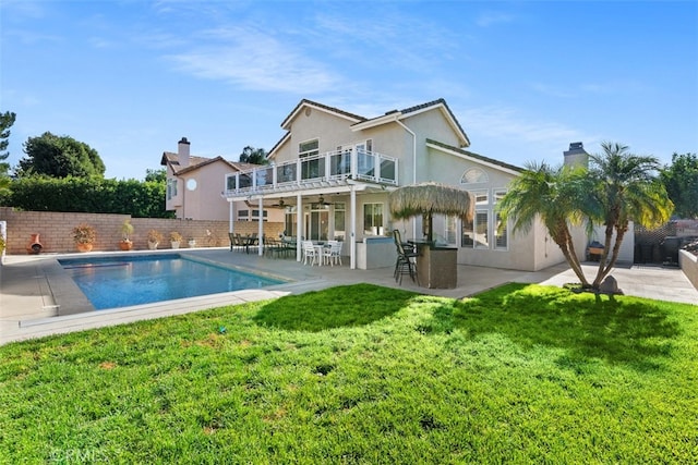 back of property featuring a fenced in pool, a yard, a patio, and a balcony