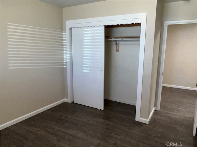 unfurnished bedroom with dark wood-type flooring and a closet