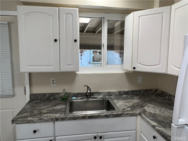 kitchen with white cabinetry, sink, and dark stone counters