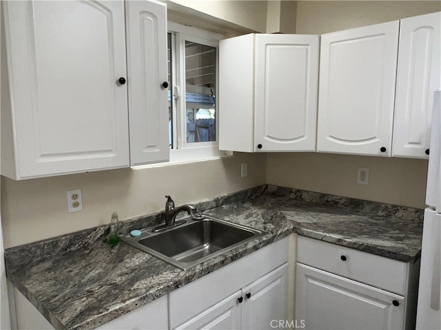 kitchen with white cabinets, dark stone countertops, and sink