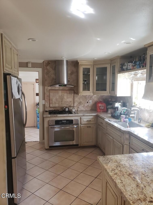 kitchen featuring light tile patterned floors, cream cabinets, wall chimney exhaust hood, decorative backsplash, and stainless steel appliances