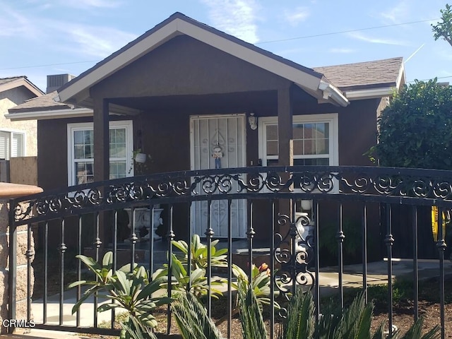 view of front of home featuring roof with shingles, stucco siding, and a fenced front yard