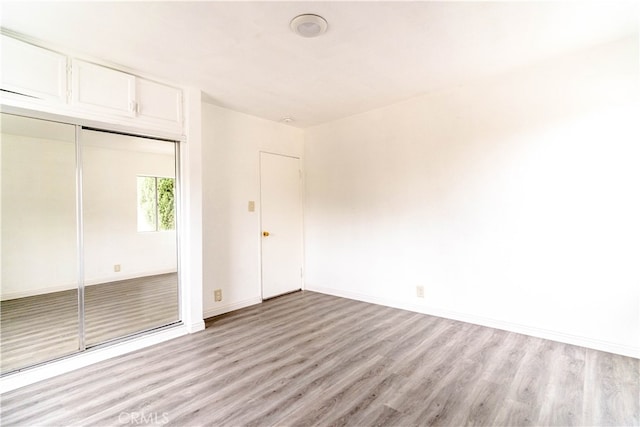 unfurnished bedroom with light hardwood / wood-style flooring and a closet