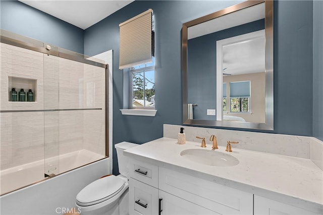 full bathroom featuring a healthy amount of sunlight, vanity, combined bath / shower with glass door, and toilet