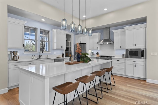 kitchen with wall chimney range hood, a center island, and white cabinets