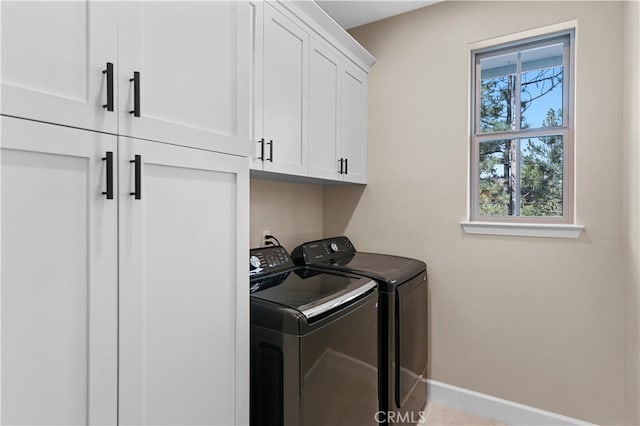 washroom featuring cabinets and washer and clothes dryer