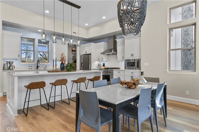 dining room with sink, a notable chandelier, and light hardwood / wood-style flooring