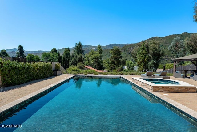 view of pool featuring a patio area, an in ground hot tub, and a mountain view