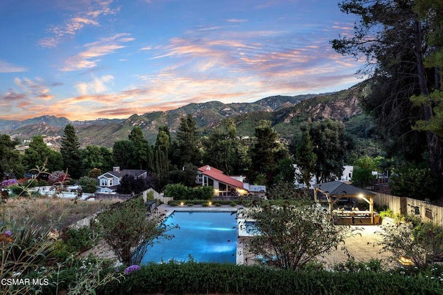 pool at dusk featuring a gazebo and a water and mountain view